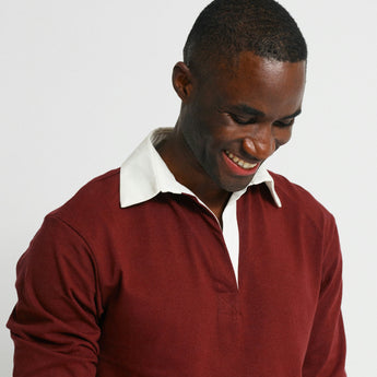 Man wearing a red sweater over a white shirt on a light gray background